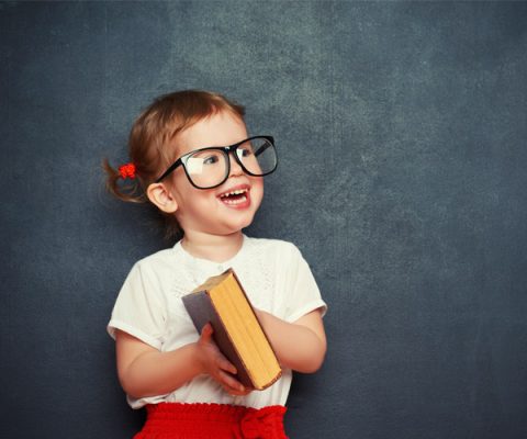 Criança com óculos e um livro nas mãos