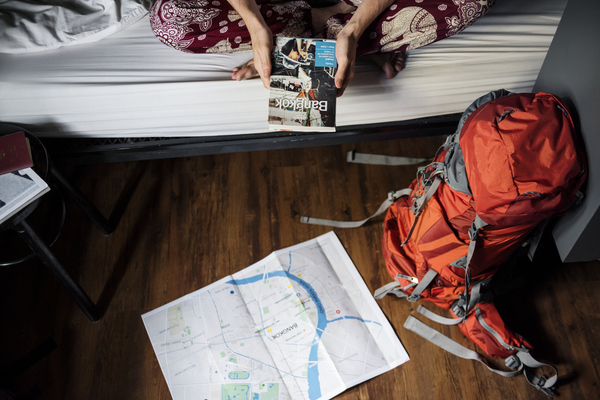 Pessoa sentada num quarto de hostel segurando um mapa