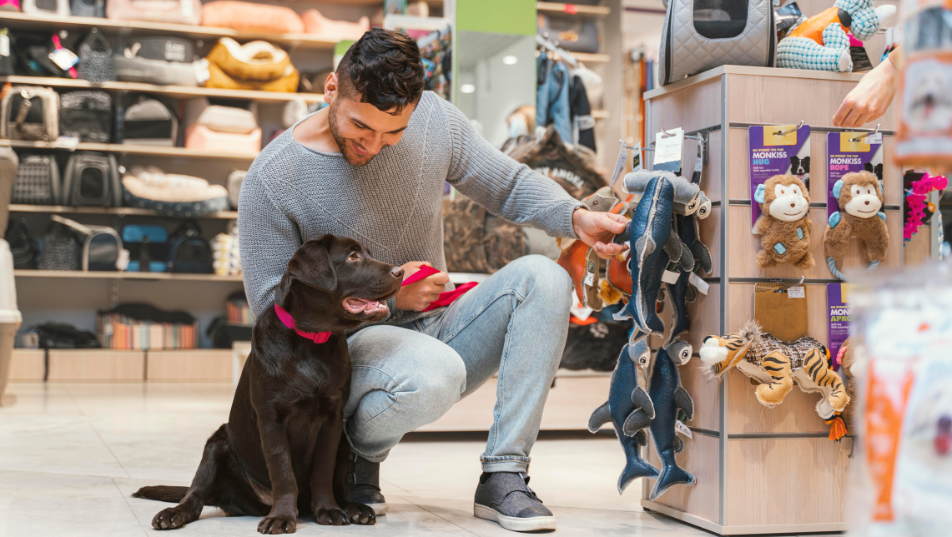 Uomo con il suo cane all’interno di un negozio di animali mentre sceglie accessori per animali domestici.